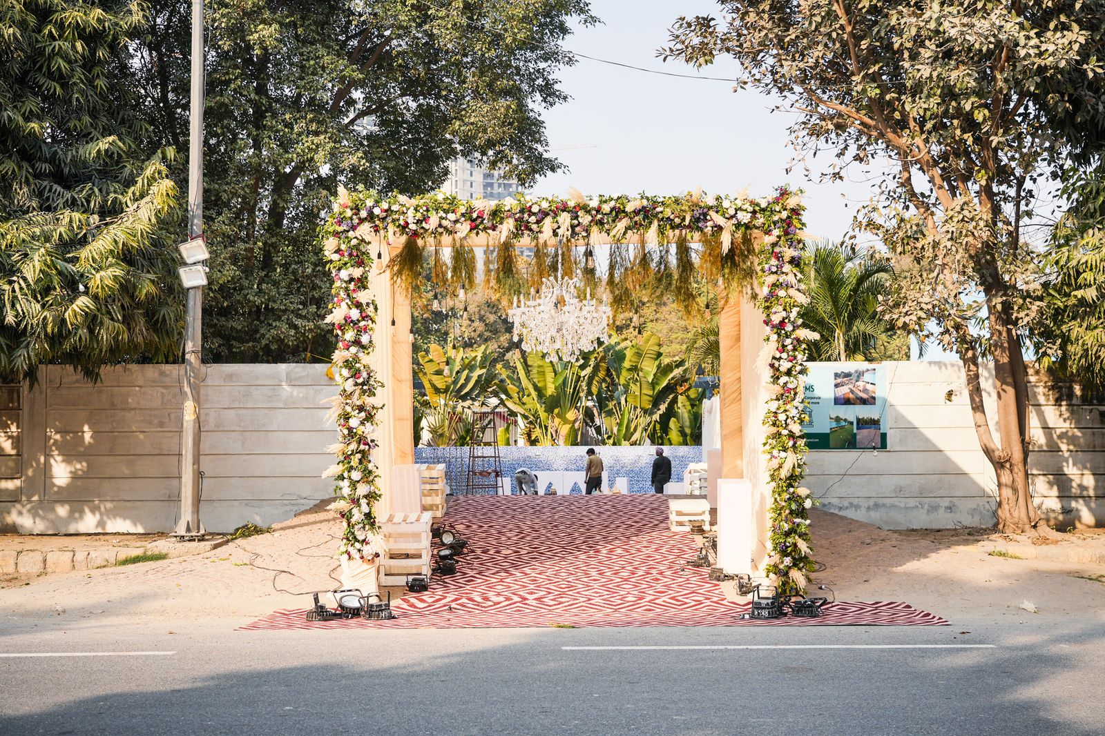 Outdoor family dining setup at Aarna Farms wedding lawn Noida — mirrored gold banquet table, cream velvet chairs, maroon and cream drapes with copper serve-ware for an intimate wedding lunch